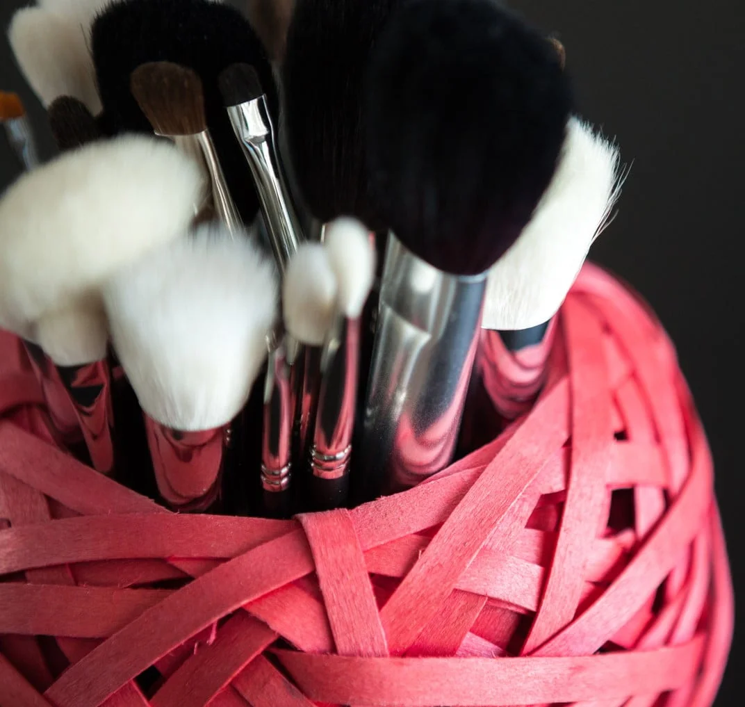 Conjunto-brochas-maquillaje-en-contenedor-fucsia-con-fondo-negro