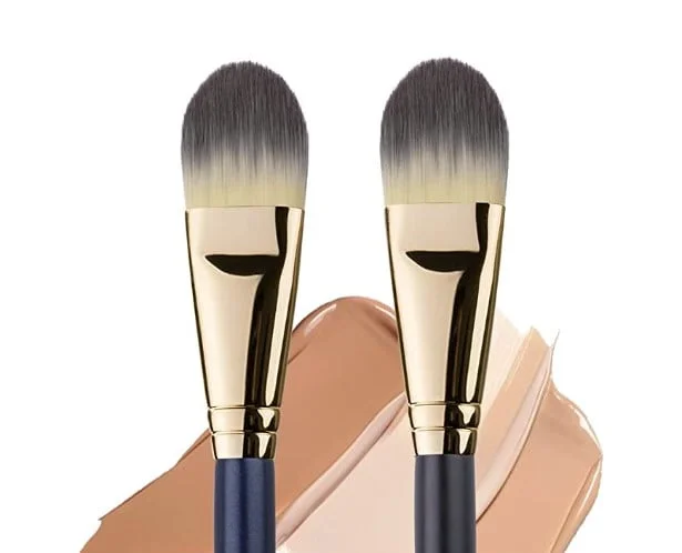 Dos brochas kabuki planas con manchas de base de maquillaje sobre fondo blanco
