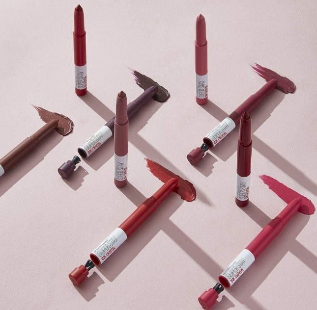 Maybelline New York SuperStay Ink Crayon Pintalabios Mate de Larga Duración de muchos colores sobre fondo rosa
