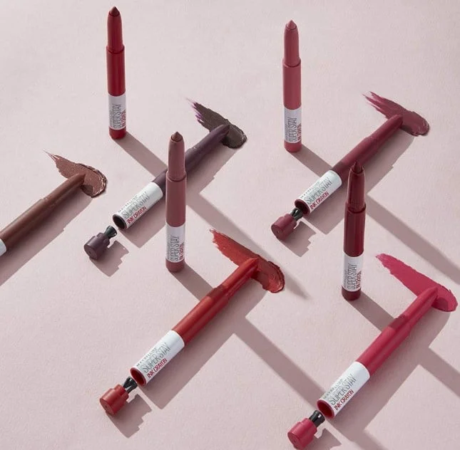 Maybelline New York SuperStay Ink Crayon Pintalabios Mate de Larga Duración de muchos colores sobre fondo rosa