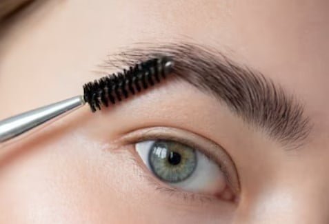 Ojo de mujer con un peine de cejas 