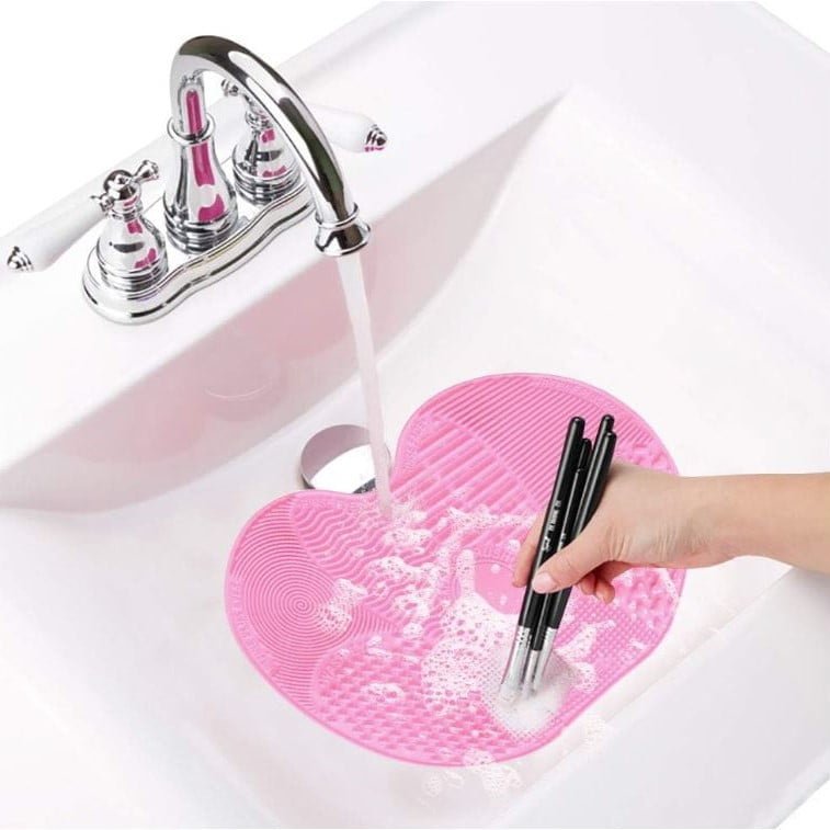 Foto de alguien limpiando brochas de maquillaje bajo el grifo