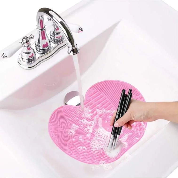Foto de alguien limpiando brochas de maquillaje bajo el grifo