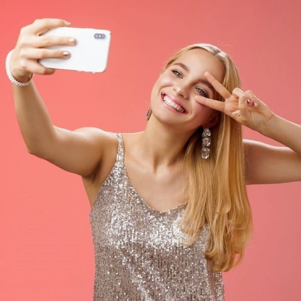 Selfie de chica con vestido de lentejuelas y fondo salmon