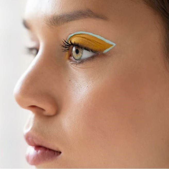 mujer llevando sombra de ojos amarillo y turquesa